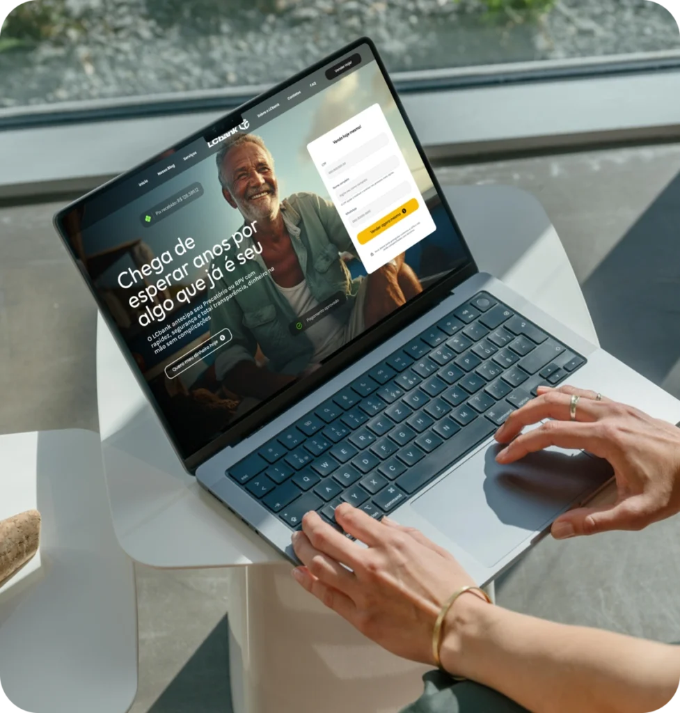 Laptop aberto no site do LCbank, com homem sorridente e texto "Chega de esperar por algo que já é seu