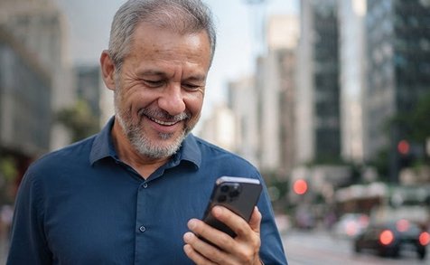 Homem sorridente com smartphone na rua da cidade
